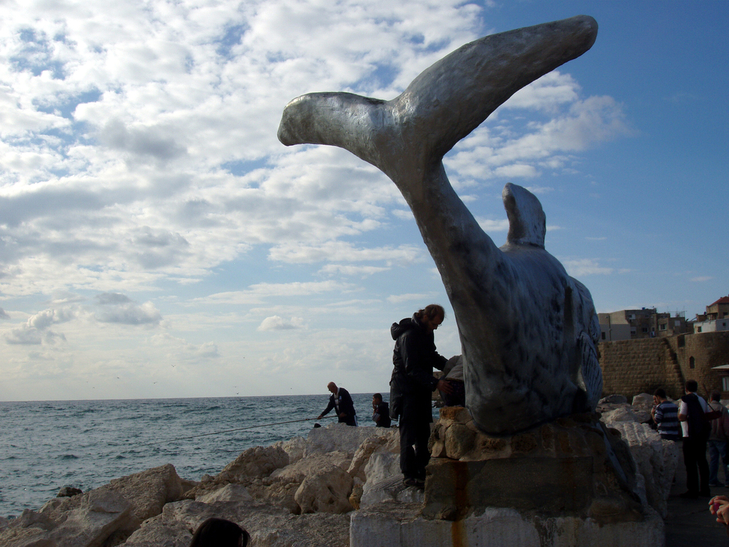 Рыбаки рядом со скульптурой "дырявого" кита в Акко.
